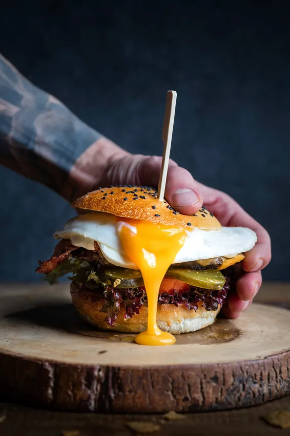 Burger trzymany w dłoniach