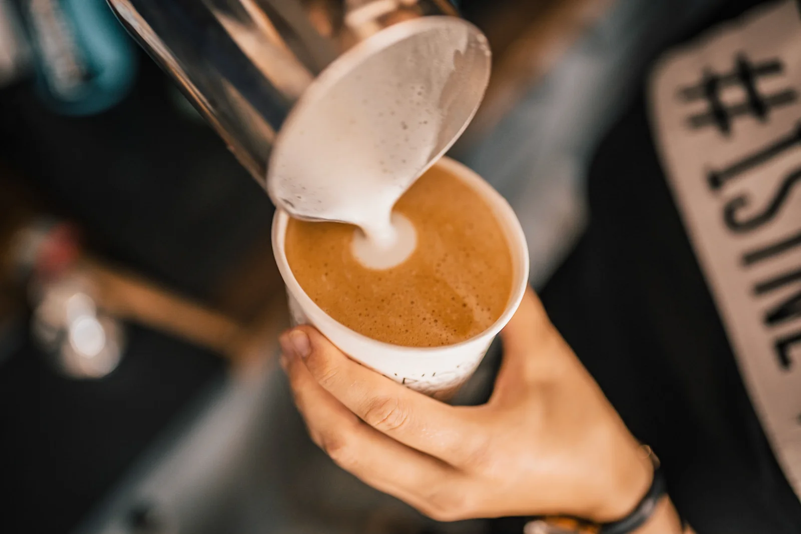 Barista wlewający mleko do filiżanki kawy